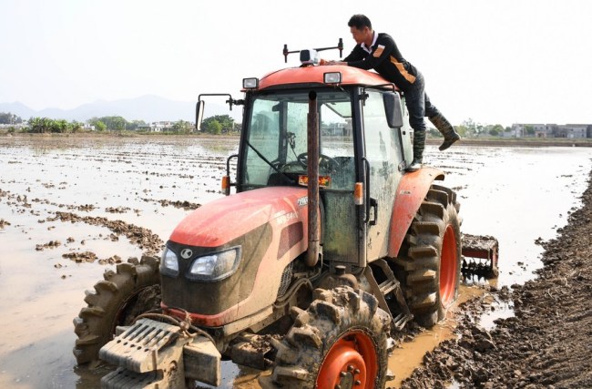 Një anëtar i kooperativës së bujqësisë ekologjike duke kontrolluar traktorin në fshatin Jiaoyi në qytetin Taishan të provincës Guangdong të Kinës Jugore, 12 mars 2021 (foto nga "Xinhua")
