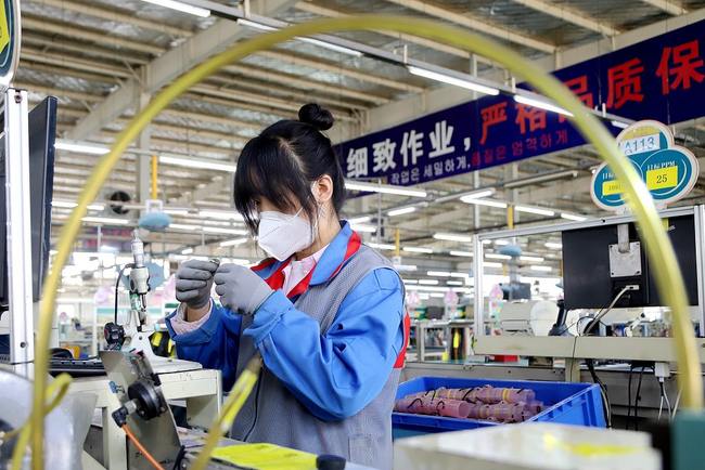 Një punonjëse në një kompani me investime të huaja në qytetin Qingdao të Kinës Jugore ishte e zënë për porositjen e pjesës së këmbimit të automjeteve, më 22 mars 2022/ VCG