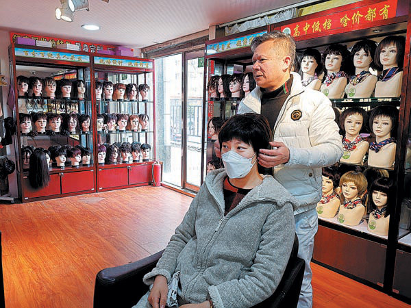 Wang i vendos një paruke një klienti. Foto nga Xinhua