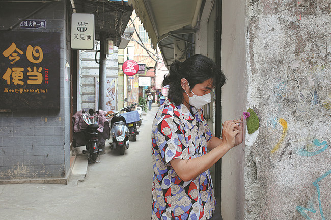 Luo Shengtian "mbjell" një lule të shajaktë në një cep muri të thyer në fshatin Nanting në qytetin Guangzhou të provincës Guangdong të Kinës Jugore. / foto nga "China Daily"