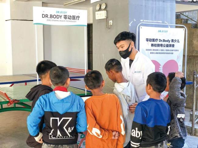 Rex Ma Chun-hung (me fustan të bardhë) ekzaminon shtyllën kurrizore të një djali në një ngjarje bamirësie për shqyrtimin e skoliozës në 2021./China Daily