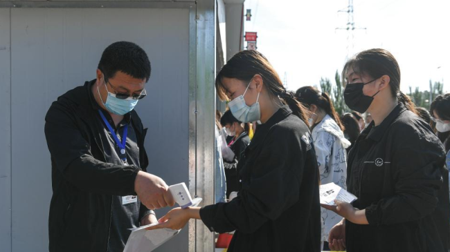 Snímek: Zkoušeným studentům je před vstupem na místo zkoušky na střední škole ve městě Chifeng (Čch´-feng) v autonomní oblasti Vnitřní Mongolsko měřena tělesná teplota; 7. června 2022. / Xinhua