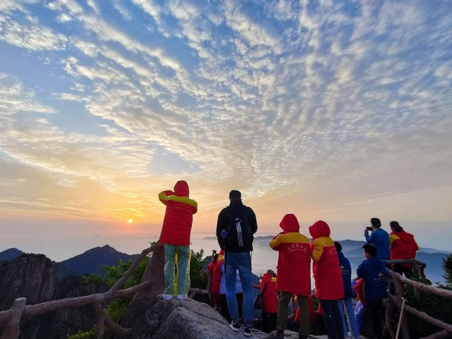 Turisté sledují východ slunce ve Žlutých horách, 5. června 2022. [Fotografie: tisková agentura Nová Čína / Xinhua]