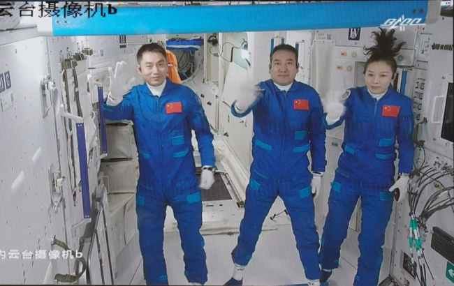 Sur cette capture d’écran prise le 16 octobre 2021 par le Centre de contrôle aérospatial de Beijing, les trois astronautes chinois font signe de la main après leur entrée dans le module central de la station spatiale Tianhe. (Photo : Tian Dingyu) 