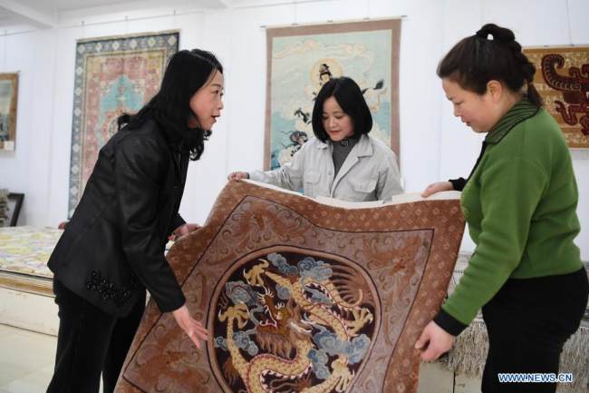 Η Χουάνγκ Τζινγκρόνγκ (1η αριστερά) και οι μαθητευόμενοι μιλούν για δεξιότητες που χρειάζονται στην ύφανση του μεταξιού στον εκθεσιακό χώρο της Xintian Silk Carpet Company στην πόλη Τιενσούι στην επαρχία Γκανσού της βορειοδυτικής Κίνας, 14 Απριλίου 2021. 