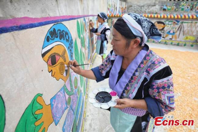 Ζωγράφοι της εθνότητας των Μιάο ζωγραφίζουν μια τοιχογραφία (壁画 Bìhuà) στο χωριό Πινγκπό της κομητείας Λονγκλί της Αυτόνομης Νομαρχίας Τσιεννάν Μπουγί και Μιάο, στην επαρχία Γκουιτζόου της νοτιοδυτικής Κίνας, στις 15 Σεπτεμβρίου 2021