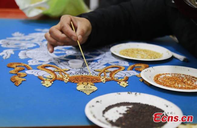 Μια Θιβετιανή δημιουργεί έργα τέχνης με σπόρους όπως κριθάρι, σιτάρι και ελαιοκράμβη, στην κομητεία Τζιαντζά, στην αυτόνομη θιβετιανή νομαρχία Χουανγκνάν της επαρχίας Τσινγκχάι της βορειοδυτικής Κίνας, 8 Δεκεμβρίου 2021. (Φωτογραφία: China News Service)