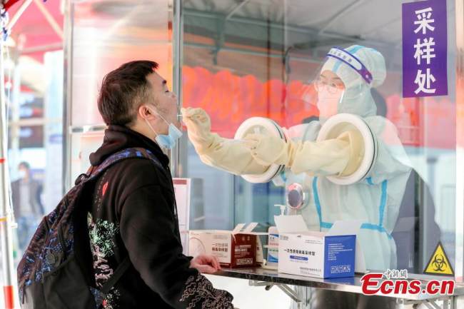 Ιατρός παρέχει υπηρεσία δοκιμής νουκλεϊκού οξέος σε έναν επιβάτη στο σιδηροδρομικό σταθμό Ναντσάνγκ στην επαρχία Τζιανγκσί της ανατολικής Κίνας, 3 Ιανουαρίου 2021. (Φωτογραφία/China News Service)