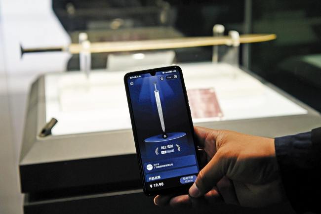 Ένας επισκέπτης συγκρίνει την ψηφιακή έκδοση του ξίφους του Γκόου Τζιεν στο κινητό του τηλέφωνο με αυτήν που εκτίθεται στο Επαρχιακό Μουσείο Χουμπέι στο Γουχάν, της επαρχίας Χουμπέι. (φωτογραφία/CHINA DAILY)