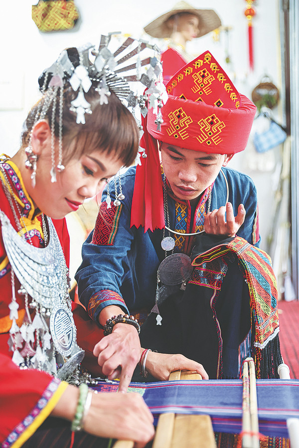 Ο Χουάνγκ Γιανγκγουέι (δεξιά), ιδιοκτήτης ενός καταστήματος ενδυμασιών μπροκάρ της εθνότητας των Λι (Li brocade) στην κομητεία Γουτζισάν, στην επαρχία Χαϊνάν, δίνει οδηγίες σε μια εκπαιδευόμενη. (φωτογραφία/XINHUA)