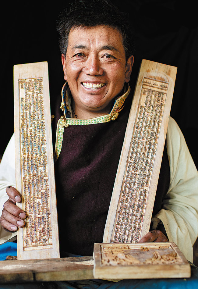 Ο Κάρμα Τσόντρακ, ένας κληρονόμος άυλης κληρονομιάς της χειροποίητης χαρακτικής Πούσουμ, δείχνει τα έργα του στο εργαστήριό του στην κομητεία Νιέμο της Λάσα.[Φωτογραφία/Xinhua]