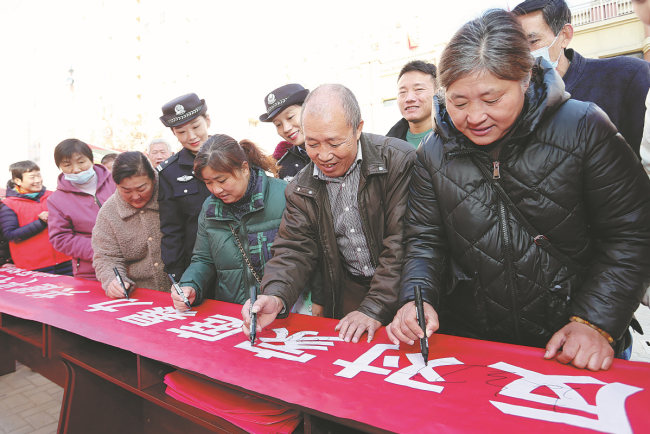 Κάτοικοι στο Χουαμπέι, Ανχούι, υπογράφουν με τα ονόματά τους σε ένα πανό κατά της ενδοοικογενειακής βίας. [Φωτογραφία από τον Wang Shanchao/For China Daily]