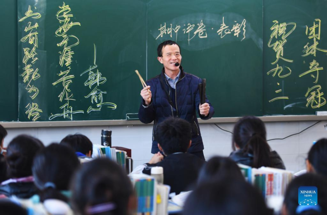 Ο Λου Γουεντζιάν αφηγείται ιστορίες με την συνοδεία του κουαϊμπάν που είναι ένα μουσικό όργανο από μπαμπού, στην τάξη του στο σχολείο της περιοχής Σανγκτσιό, στην επαρχία Χενάν της κεντρικής Κίνας, στις 2 Δεκεμβρίου 2021. (Xinhua/Zhang Haoran)
