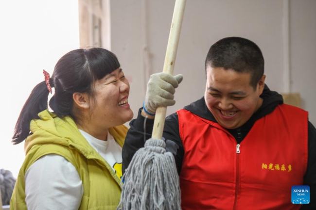 Η Τιεν Λιτσάο (αριστερά) συνομιλεί με έναν νεαρό με αναπηρία στο κέντρο απασχόλησης για άτομα με ειδικές ανάγκες στην περιοχή Μπαοντί, στο Τιεντζίν της βόρειας Κίνας, σε φωτογραφία από την 1η Μαρτίου 2022. 