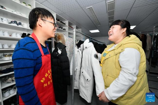 Η Τιεν Λιτσάο (δεξιά) συνομιλεί με έναν νεαρό με αναπηρία στο κέντρο απασχόλησης για άτομα με ειδικές ανάγκες στην περιοχή Μπαοντί, στο Τιεντζίν της βόρειας Κίνας, σε φωτογραφία από την 1η Μαρτίου 2022. 