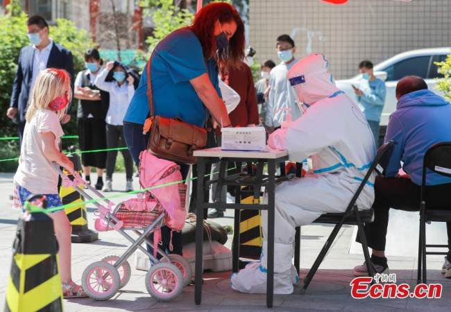 Μέλος του ιατρικού προσωπικού βοηθά αλλοδαπούς υπηκόους να καταχωρήσουν τις πληροφορίες τους για τεστ νουκλεϊκού οξέος στην συνοικία Σανλιτούν της περιοχής στην πρωτεύουσα της Κίνας, στις 15 Μαΐου 2022. (Φωτογραφία: China News Service) 