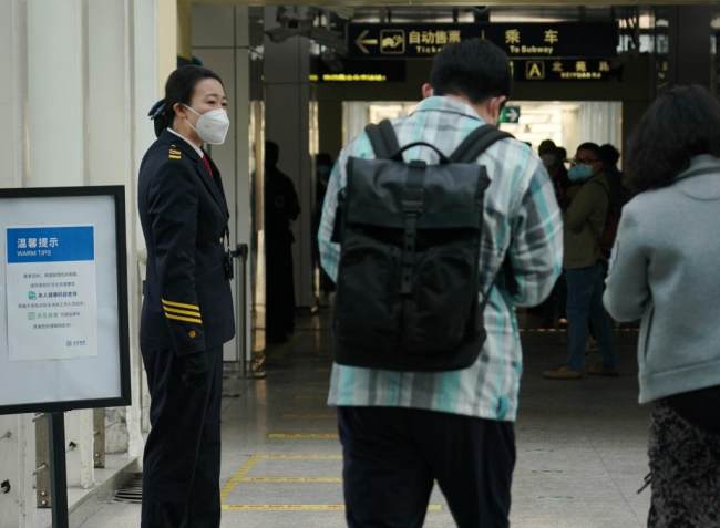 Προσωπικό του σταθμού υπενθυμίζει στους επιβάτες να δείχνουν τον κωδικό QR υγείας σε σταθμό του μετρό στο Πεκίνο, πρωτεύουσα της Κίνας, 17 Μαΐου 2022. 