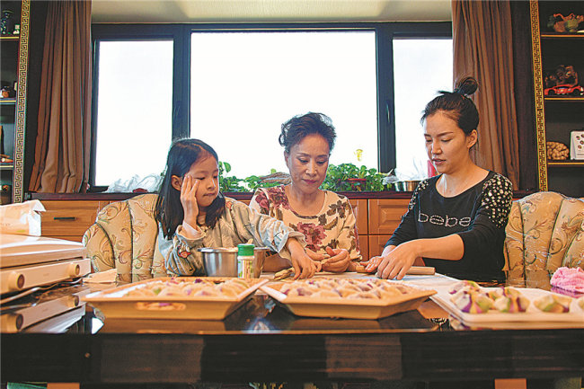 Η Γκουό Λιρόνγκ φτιάχνει ντάμπλινγκ με την κόρη και την εγγονή της στο σπίτι. [Φωτογραφία/ China Daily]