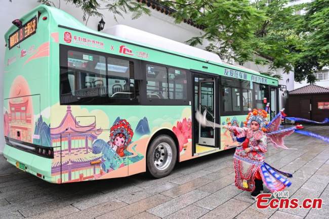 Ένα παιδί δίνει παράσταση καντονέζικης όπερας μπροστά από ένα θεματικό λεωφορείο στο Γκουανγκτζόου (Καντόνα), στην επαρχία Γκουανγκντόνγκ της νότιας Κίνας, 8 Ιουνίου 2022. Το λεωφορείο Ν. 8, με θέμα την όπερα ξεκίνησε επίσημα τις διαδρομές του στο Γκουανγκτζόου την προηγούμενη Τετάρτη. (Φωτογραφία: China News Service)