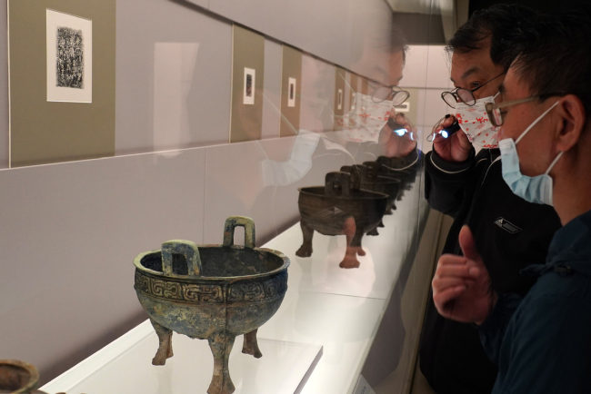 Επισκέπτες στην έκθεση με τίτλο « Ο Θρύλος των Κοιλάδων Χαν και Χουάι: Χάλκινα σκεύη του κράτους των Ε» στο Μουσείο της Σαγκάης στις 19 Οκτωβρίου 2021. [Φωτογραφία/Xinhua]