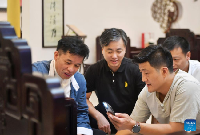 Ο Τσεν Γιουσού (1ος αριστερά) μιλάει για την τέχνη της κλασικής επιπλοποιίας με μερικούς συνεχιστές της ξυλογλυπτικής τέχνης επαρχιακού επιπέδου στο Πουτιέν, της επαρχίας Φουτζιέν στην νοτιοανατολική Κίνα, σε φωτογραφία από τις 10 Ιουνίου 2022. (φωτογραφία/Xinhua)