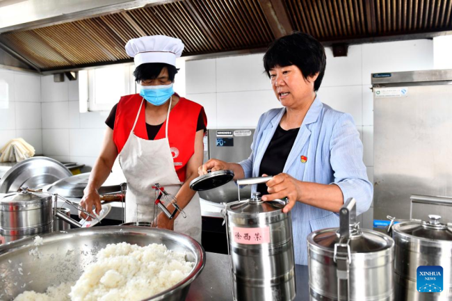 Η Τζανγκ Σοουγίνγκ (δεξιά) μαθαίνει για τα γεύματα στην κουζίνα ενός κέντρου φροντίδας ηλικιωμένων στο χωριό Χονγκνίγια στην κομητεία Γουλιέν του Ριτζάο, στην επαρχία Σαντόνγκ της ανατολικής Κίνας, 17 Ιουνίου 2022.