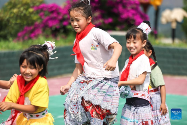 Η Γιανγκ Γιαμένγκ (κέντρο) παίζει με τους συμμαθητές της σε ένα δημοτικό σχολείο στο χωριό Χουαγού της πόλης Σινρέν Μιάο, στην πόλη Τσιανσί της επαρχίας Γκουιτζόου της νοτιοδυτικής Κίνας, 1 Ιουνίου 2022.